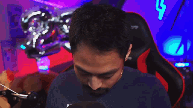 a man with a beard is sitting in a red and black racer gaming chair