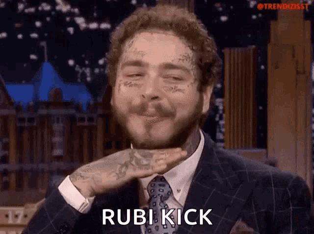 a man in a suit and tie is making a funny face and says rubi kick