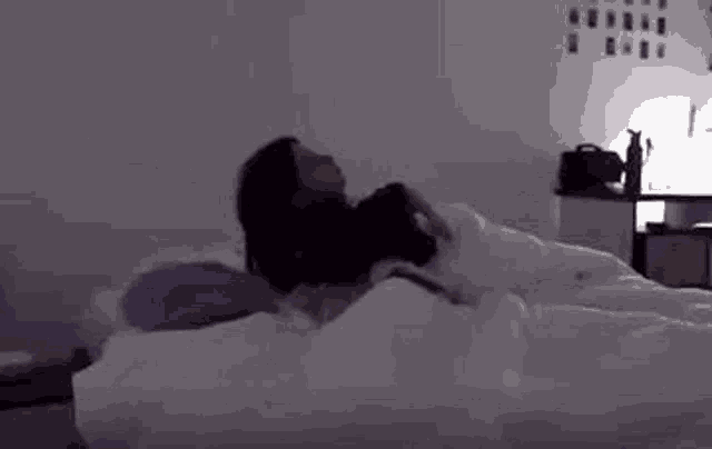 a woman is laying on a bed in the dark with a purple pillow .