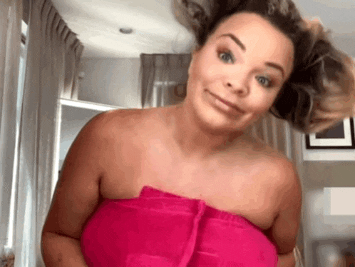 a woman is wrapped in a pink towel and making a face .