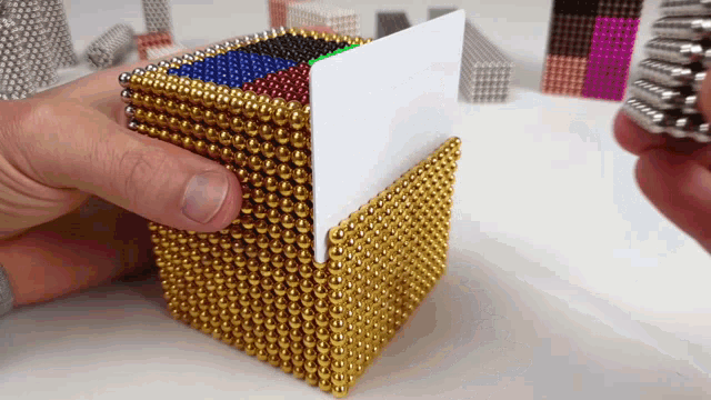 a person is holding a card in a gold cube