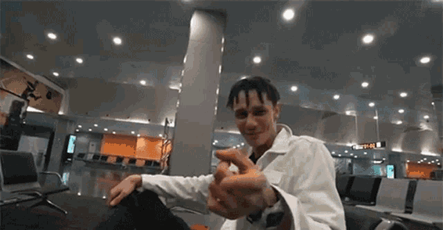 a man is sitting in a waiting room at an airport and making a heart with his hands .