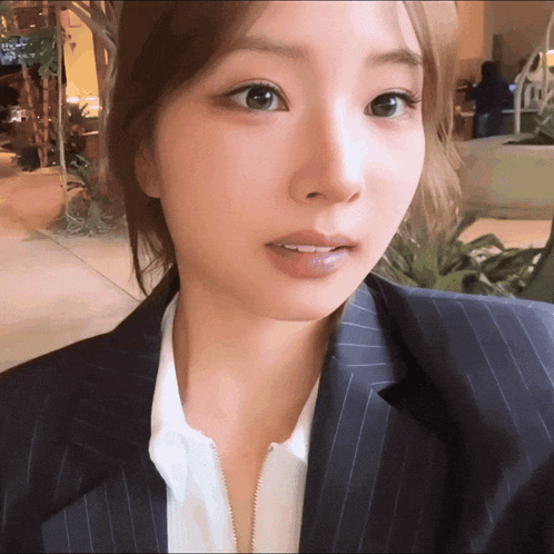 a close up of a woman 's face wearing a suit and white shirt