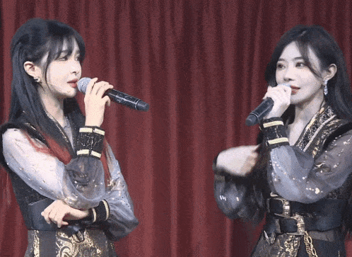 a woman singing into a microphone next to another woman singing into another microphone