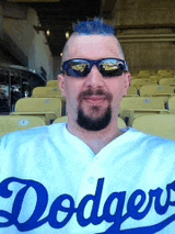 a man wearing sunglasses and a white dodgers jersey