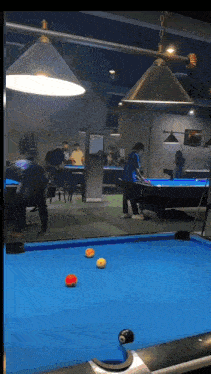 a group of people are playing pool on a blue table