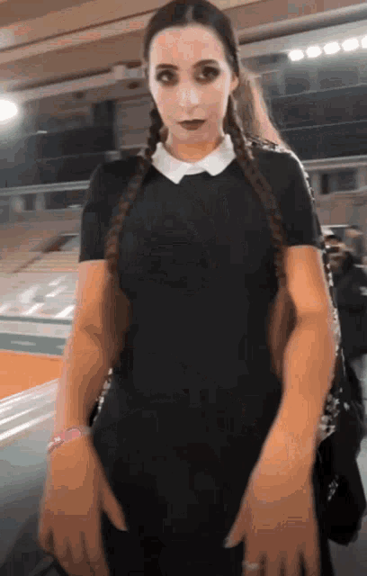a woman in a black dress with braids is standing in a stadium