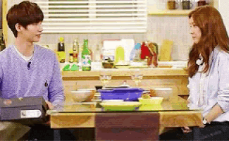 a man and a woman are sitting at a table in a kitchen talking to each other