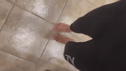 a person standing on a tiled floor with their feet bare and their pants saying tv