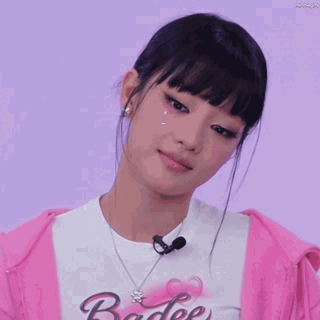a woman wearing a pink jacket and a white shirt that says badge on it