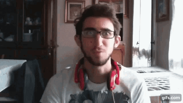 a man wearing glasses and headphones is making a face .