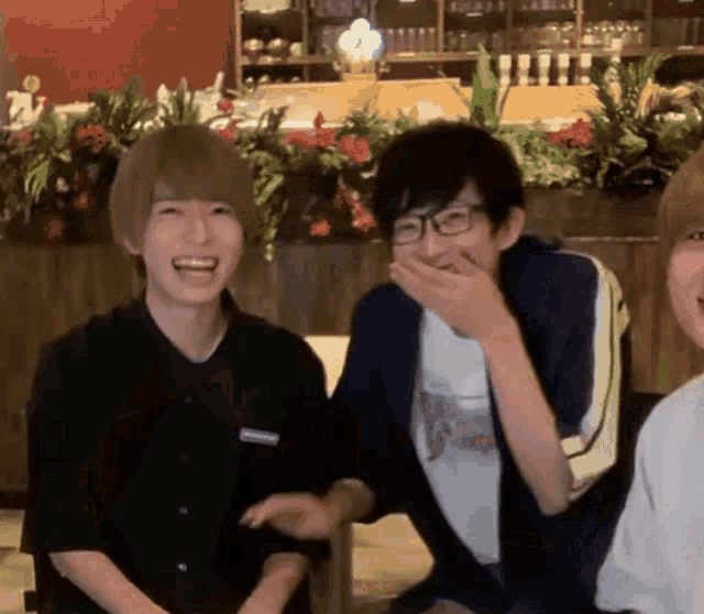 a group of young people are sitting next to each other in a restaurant laughing .