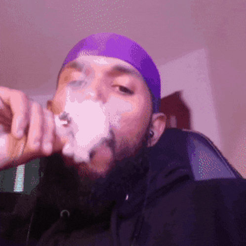 a man with a beard wearing a purple hat smoking a cigarette