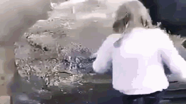 a woman is standing next to a car with smoke coming out of the hood .