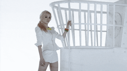 a woman in white shorts and a yellow collar is standing in front of a white cage