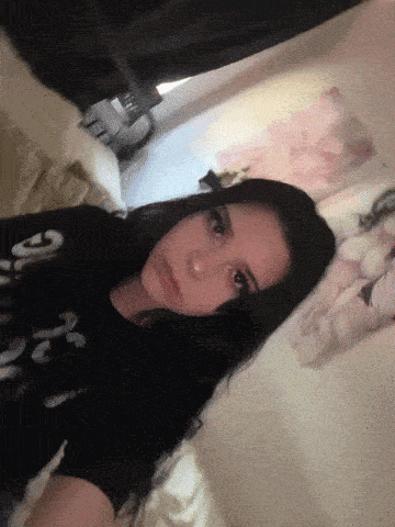a girl wearing a black shirt that says girl on it is laying on a bed