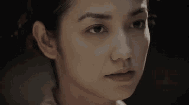 a close up of a woman 's face in a dark room looking at the camera .