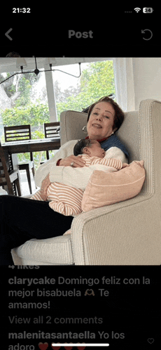 a woman is sitting in a chair holding a baby in her arms and the time is 21:32