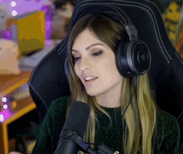 a woman wearing razer headphones sits in a chair