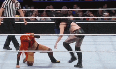 two women are wrestling in a wrestling ring with a referee watching .
