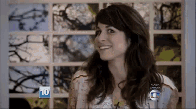 a woman is smiling in front of a wall with pictures and the number 10 is on it