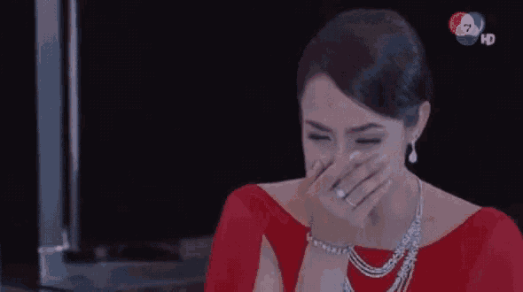 a woman in a red dress covering her mouth with her hand .