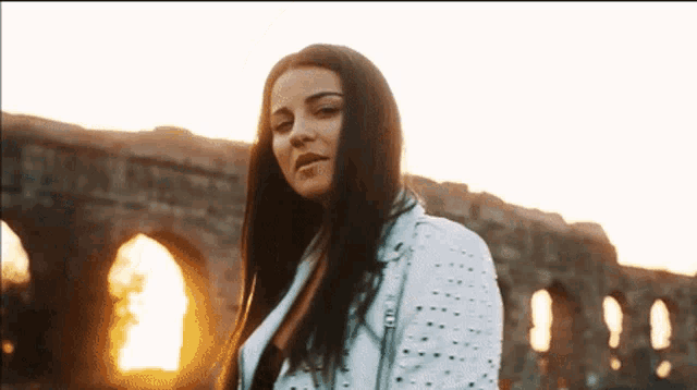 a woman in a white jacket stands in front of a building