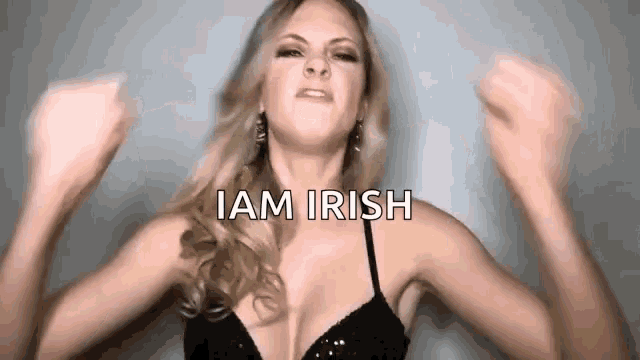 a woman in a black bra is raising her arms in the air and saying `` i am irish '' .