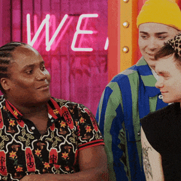 three people standing in front of a neon sign that says " we "