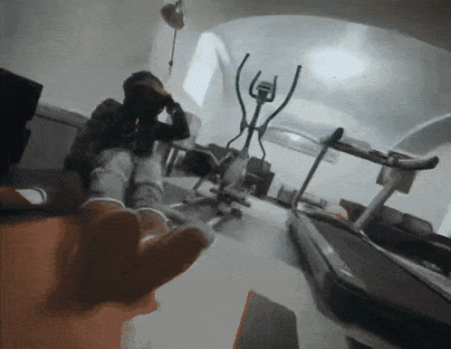 a person sitting in a room with a treadmill and an exercise bike