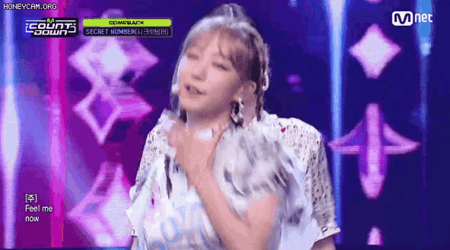 a woman in a white dress is dancing on a stage in front of a sign that says mnet .