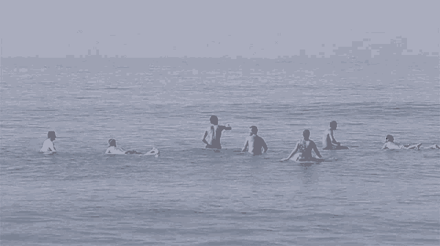 a group of people are swimming in the ocean and one man is throwing a ball