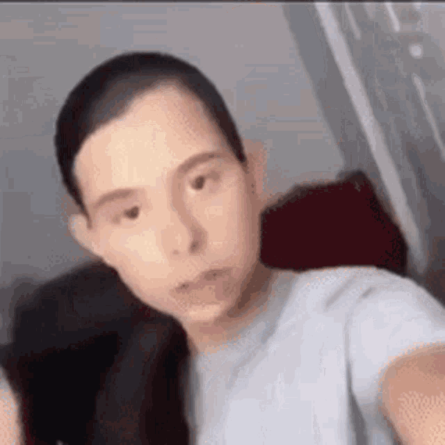a man with a shaved head is taking a selfie in a room .