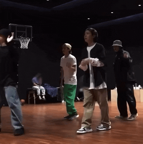 a group of people are dancing on a stage in front of a basketball hoop