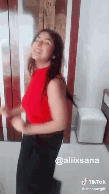 a woman in a red top and black pants is dancing in a living room .