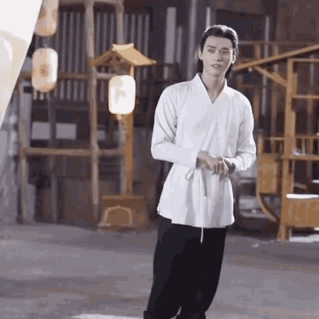a young man in a white shirt and black pants is standing in front of a building .