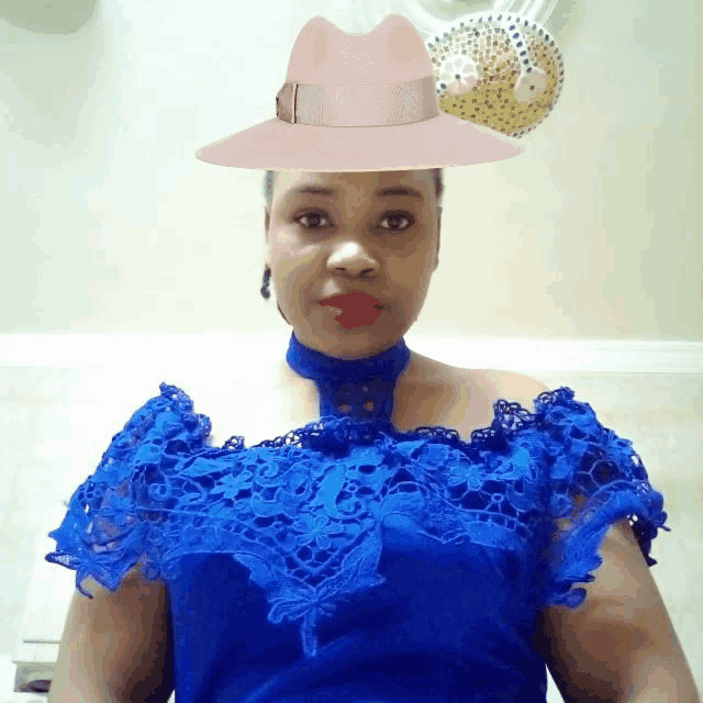 a woman wearing a blue lace off the shoulder top and a pink hat