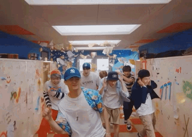 a group of young men are walking down a hallway wearing wtaps shirts