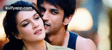 a man and a woman are standing next to each other and the woman is kissing the man on the cheek .