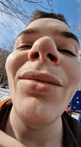 a close up of a person 's face with a blue playground in the background