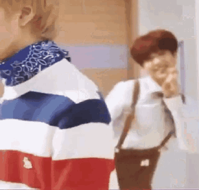a man in a red , white and blue striped sweater is standing next to another man .