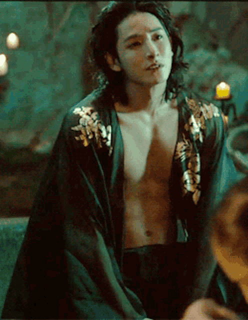 a man with long hair is wearing a black robe with gold embroidery
