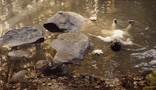 a person is floating in a body of water with rocks