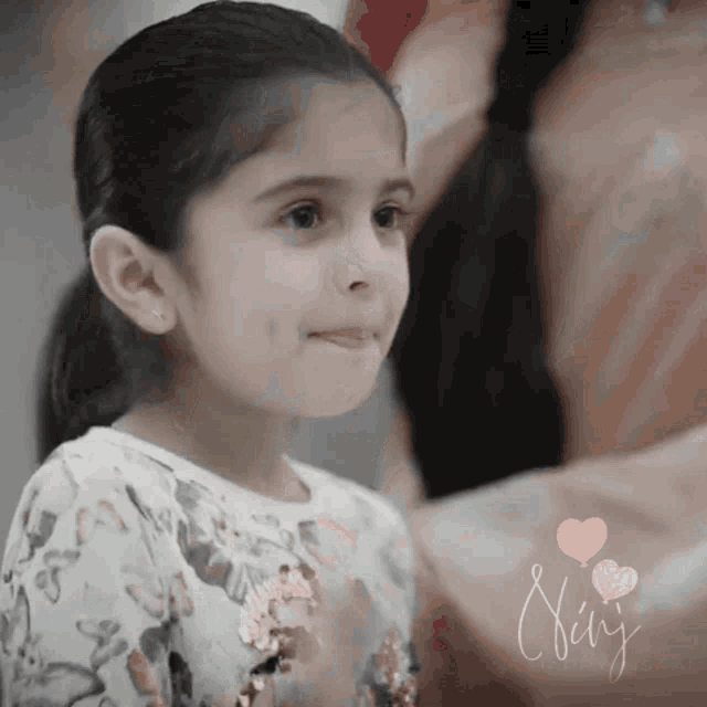 a little girl in a floral shirt is smiling with the name chris written below her