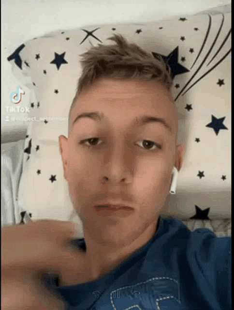 a young man wearing ear buds is laying on a pillow .