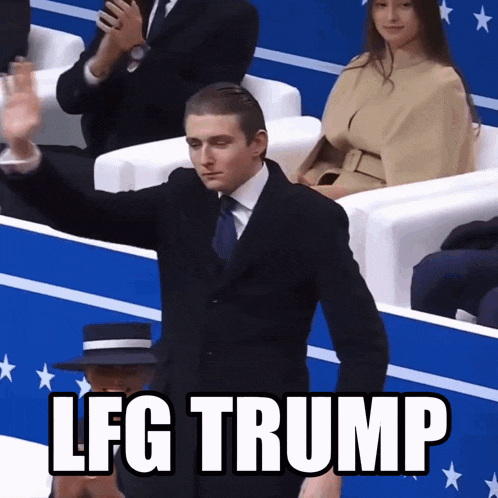 a man in a suit and tie stands in front of a crowd with the words lfg trump on the screen