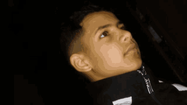 a close up of a boy 's face with a black and white jacket