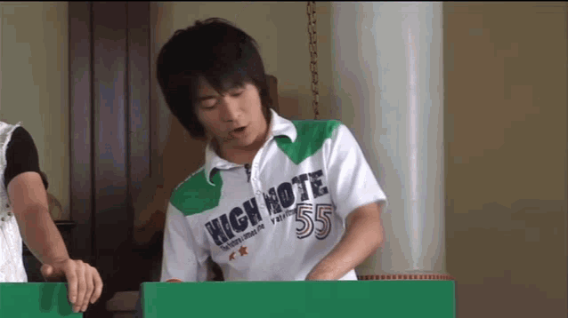 a man wearing a high note 55 shirt looks at something