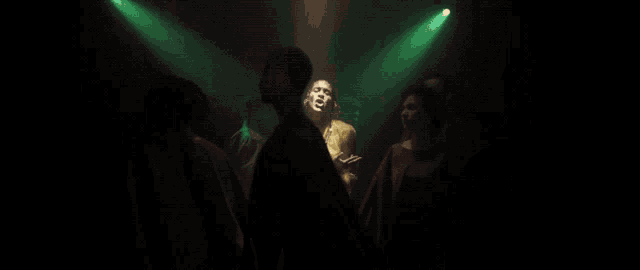 a woman in a gold dress is standing in a dark room