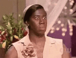a woman is making a funny face while wearing a white dress and a flower in her hair .